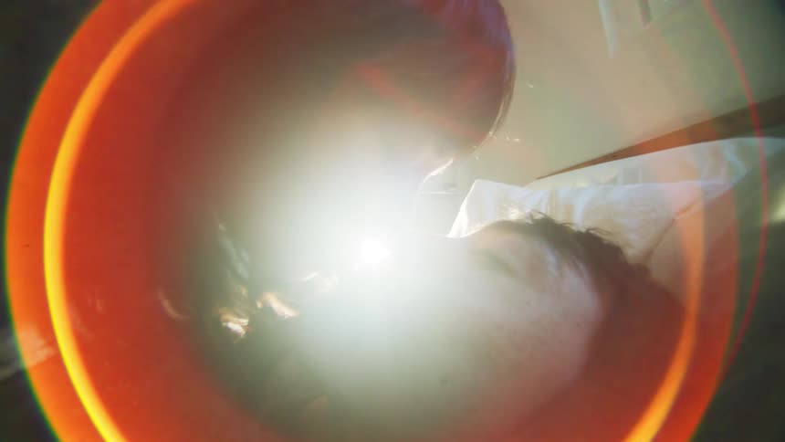 A woman kisses a man who is lying in a bed