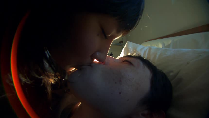 A young couple kissing in the bedroom