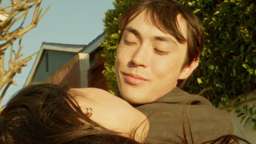 Portrait of a smiling man with his girlfriends face lying on his body while they are outdoors