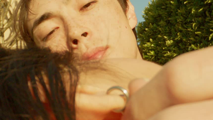 A closeup of a person touching the ear of his partner with sunlight on their skin