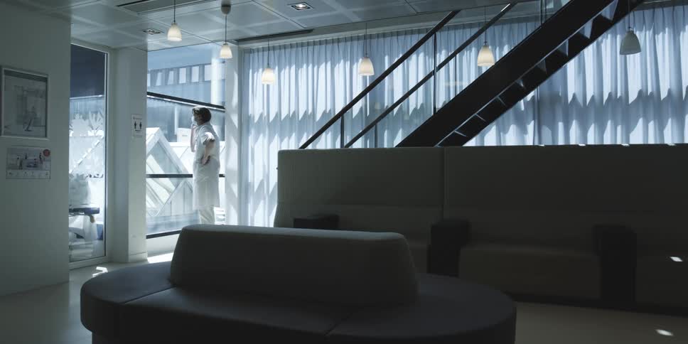 A man dressed in white talks on a phone in a room
