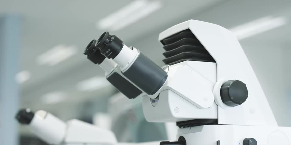 A white microscope with black lenses in a bright environment