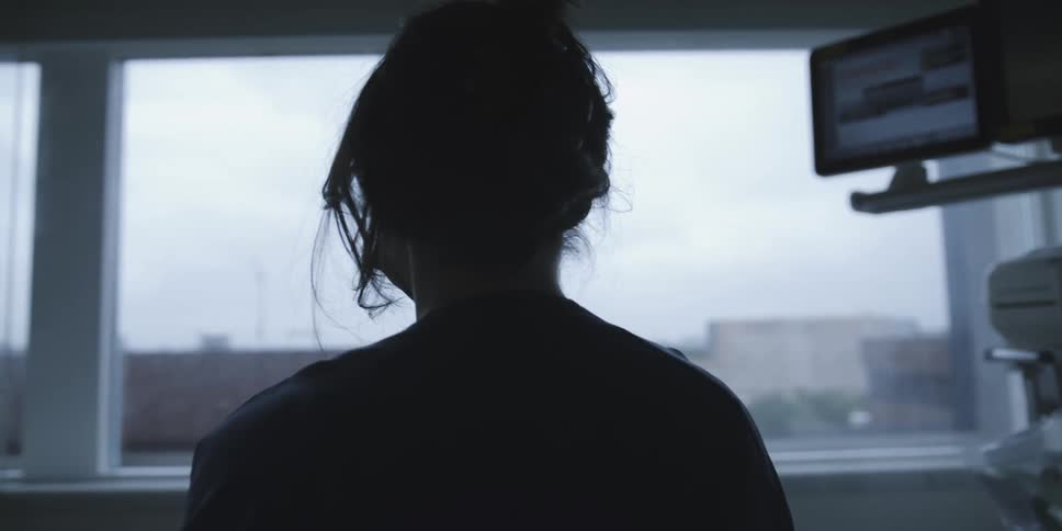 Silhouette of a healthcare professional looking out the window in a hospital setting