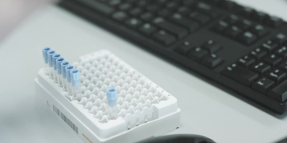 A woman manages a few test tubes at a desk