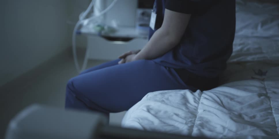 A doctor sits on the hospital bed