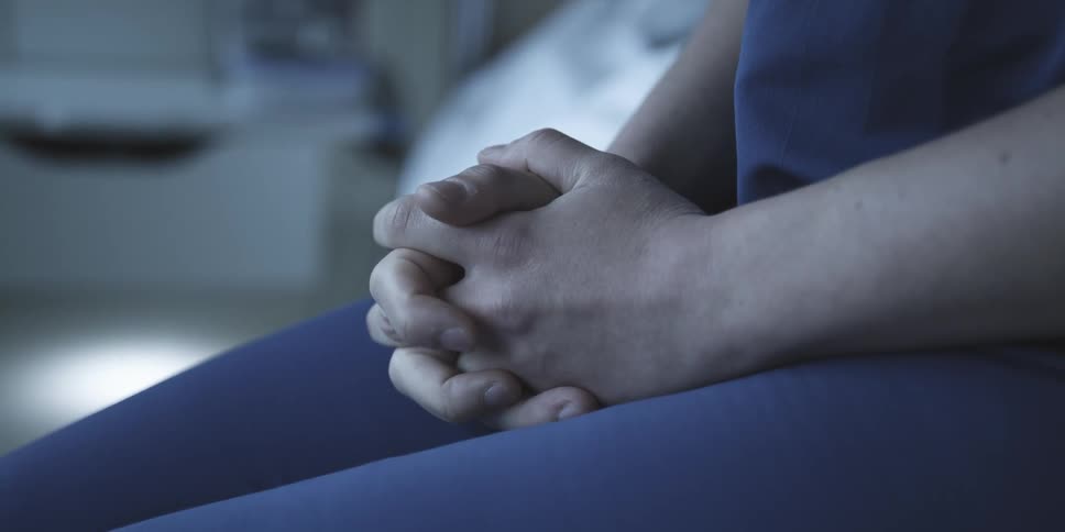 A person who is sitting and their hands are intertwined