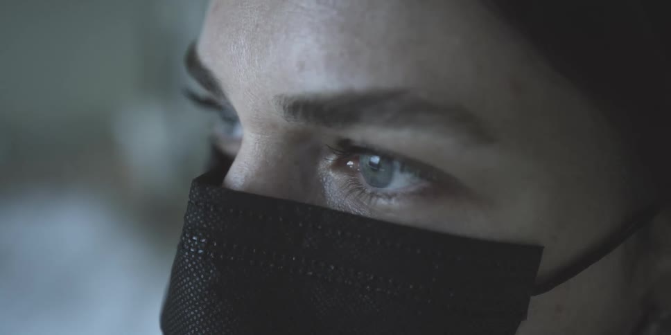 Close up of the face of a young woman wearing a black face mask