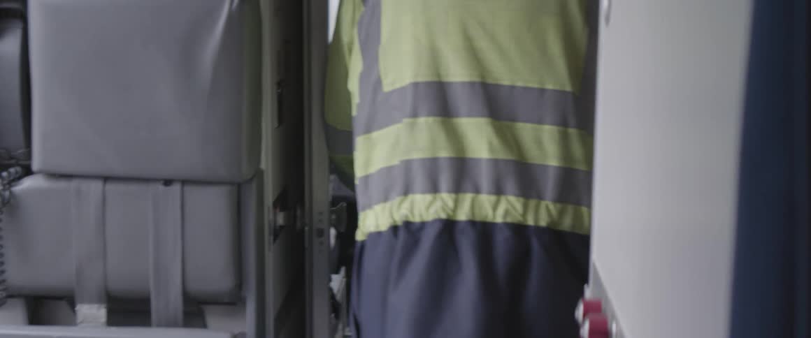 Laborer wearing a jacket walks into airplane cockpit