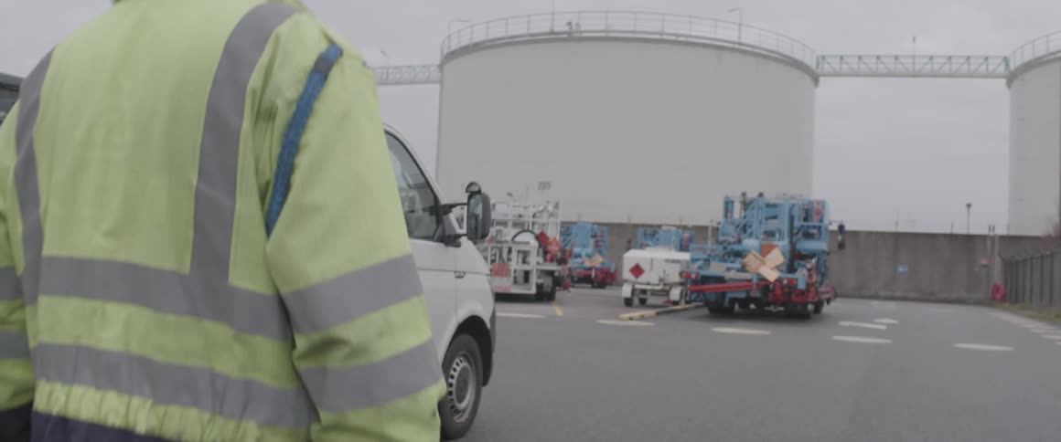 Male worker walks past equipment parked in lot near building with a safety rail on the roof