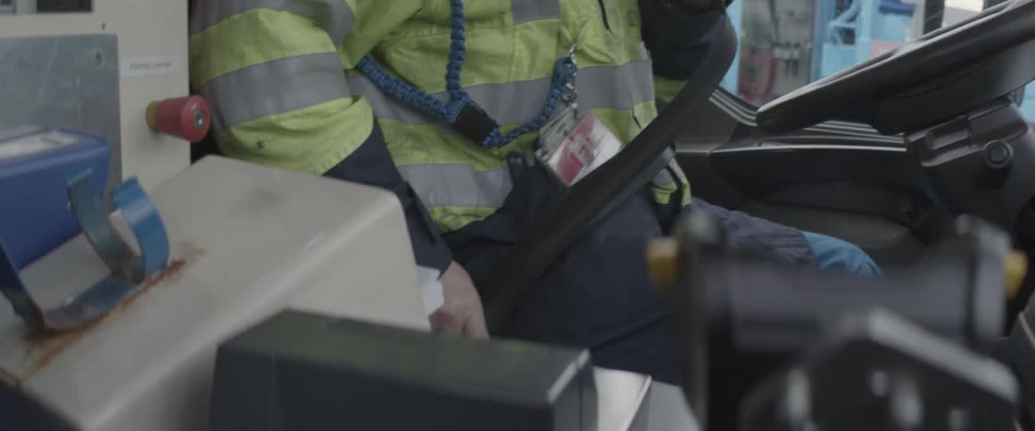Worker inside a vehicle wearing a seat belt and with equipment at his side