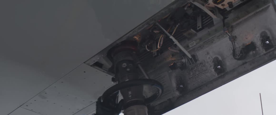 Working man taking a hose and injecting it into the fuel valve of an airplane