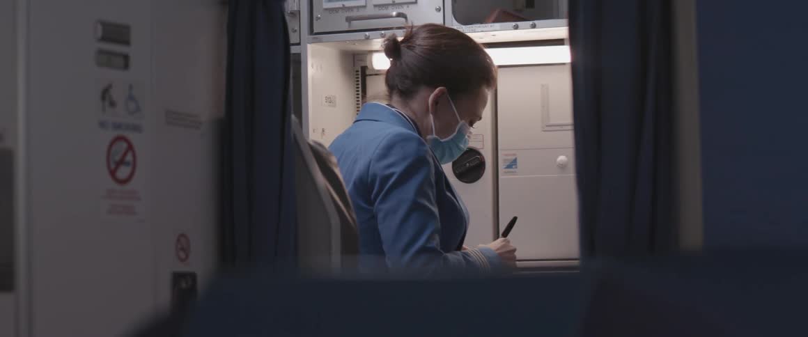 Stewardess with face mask inside a plane writing