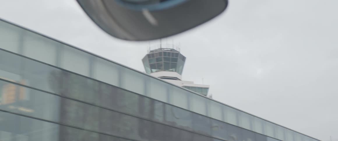 A view of an airport control tower seen through the windshield of a vehicle