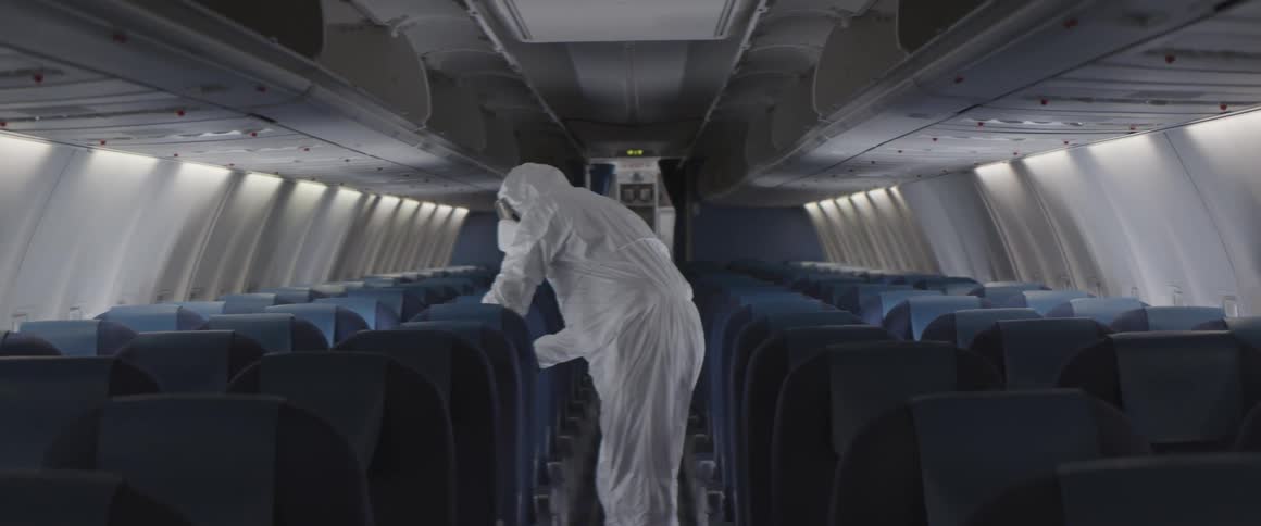 A man in a hazmat suit cleans an airplane interior
