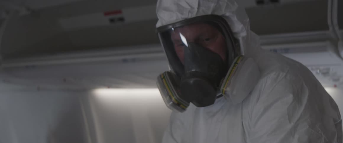 A person in protective gear working inside an airplane
