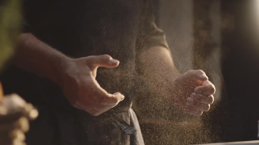 A man slaps his flour covered hands together
