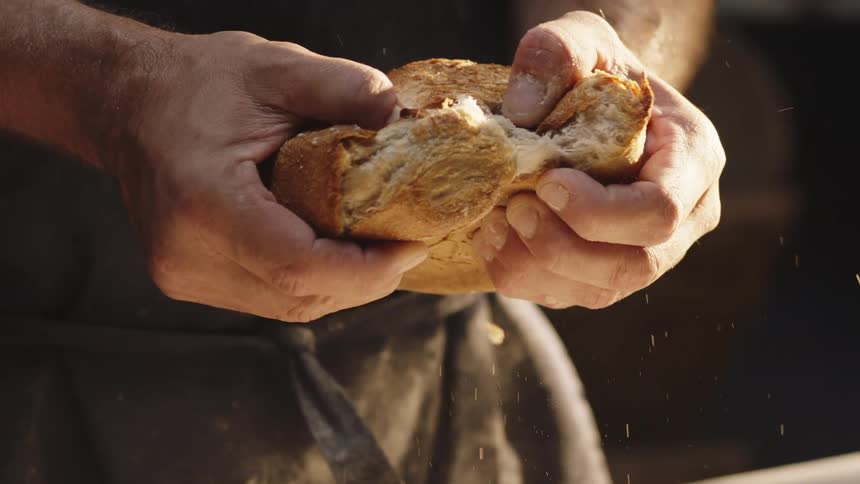 Close up of a pair of hands breaking a loaf of bread