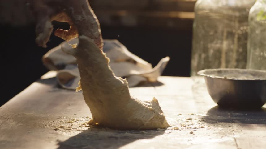 A man kneads a sticky wad of dough on a table
