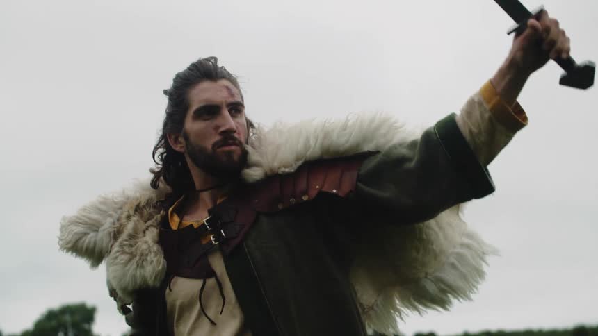 A man dressed as an ancient warrior draws a sword