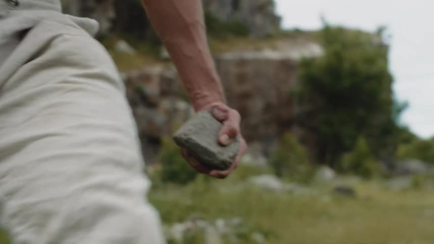 Man hand carrying a stone in a natural outdoor environment