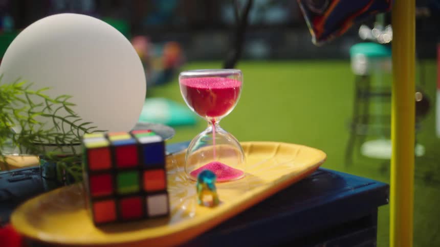 An hourglass on a tray on top of a table that stands on a green lawn