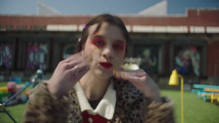 A young woman poses blows a kiss and smiles modeling clothing and makeup