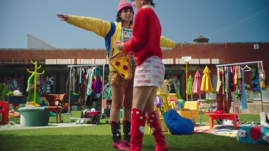A female helps another girl model clothing outside a retail store