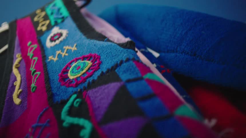 A colorful vest hangs from a rack outdoors
