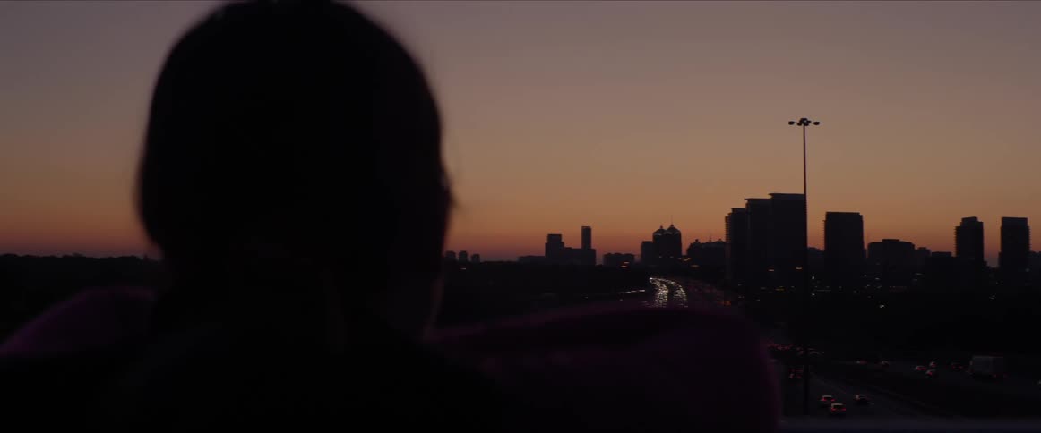 A person watches traffic driving out of a city
