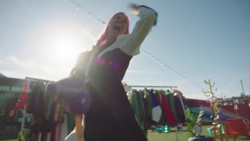 A woman acts wacky while wearing clothing outside of a clothing store