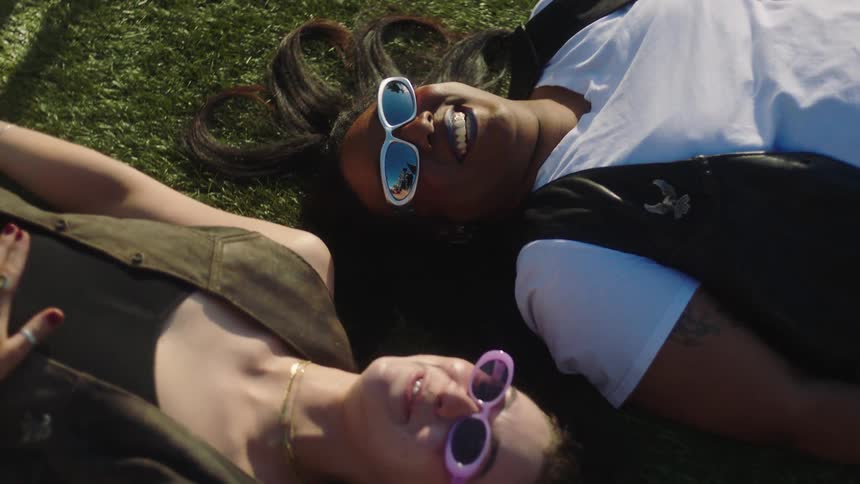 Two women lying on the grass together and laughing