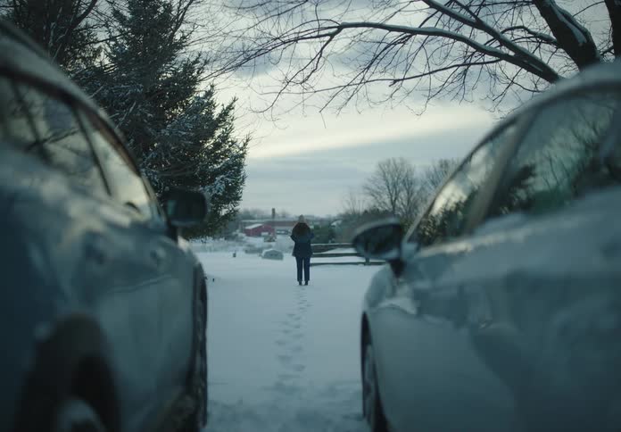 A woman walks away from two parked cars