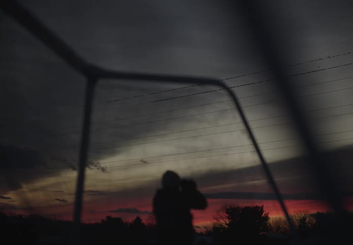 Silhouette of a person walking in an outdoor environment on a gray and reddish day in winter