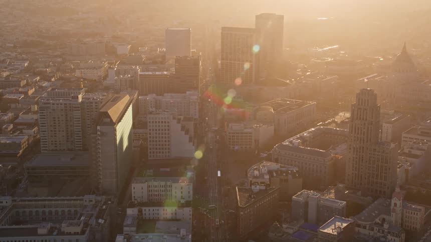 Aerial panorama of a metropolis with a skyscraper and urban buildings with reflection of late afternoon sunlight