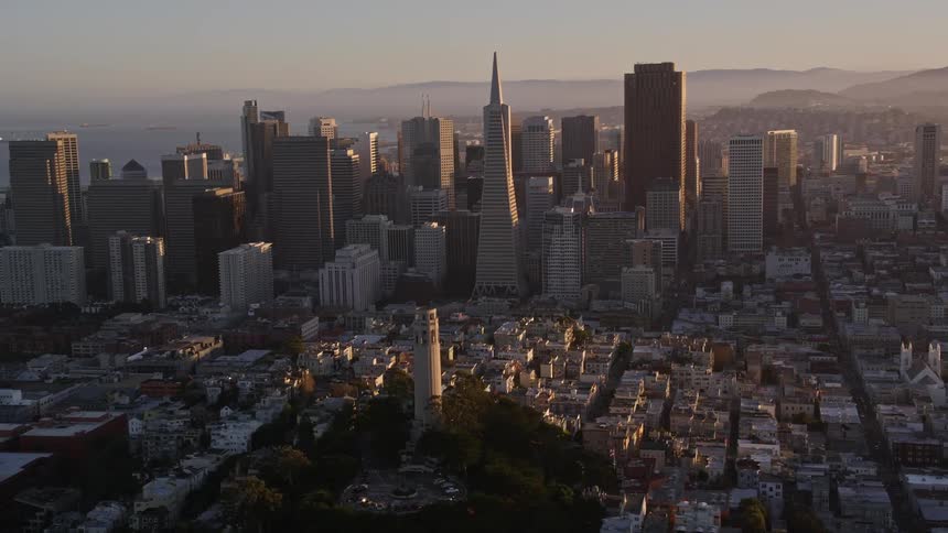 An aerial view of a city with a tower in the center and in the background a center with many tall buildings