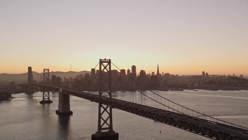 Panorama of an extensive bridge over the sea that gives access to a metropolis with skyscrapers on a morning with a red sky