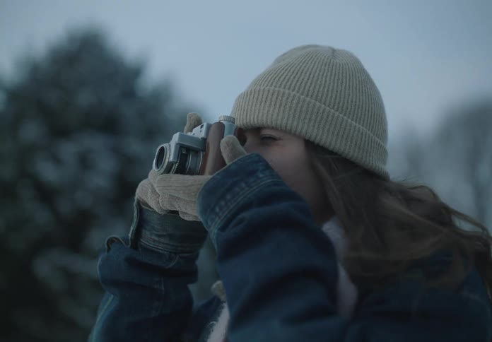 Young man in an outdoor environment in winter holding his vintage camera and taking photos