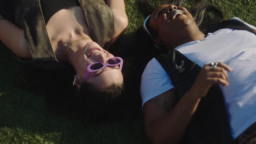 Two friends lay in the grass and laugh