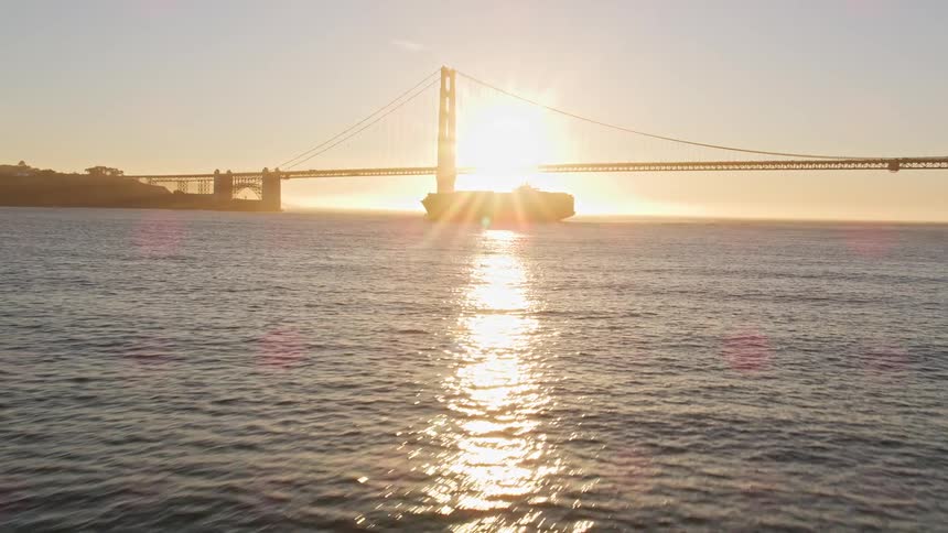 A large boat on a wide river passing over a bridge