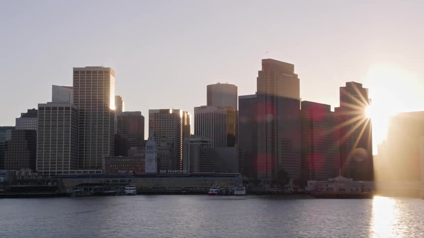 A neighborhood in a city with huge commercial buildings facing the sea and behind there is strong sunlight