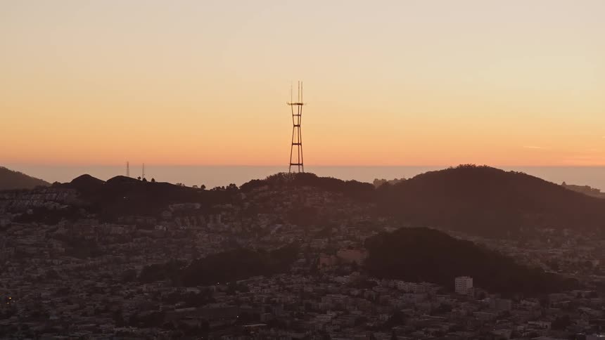 Tall metal structure towers over buildings against a red sky