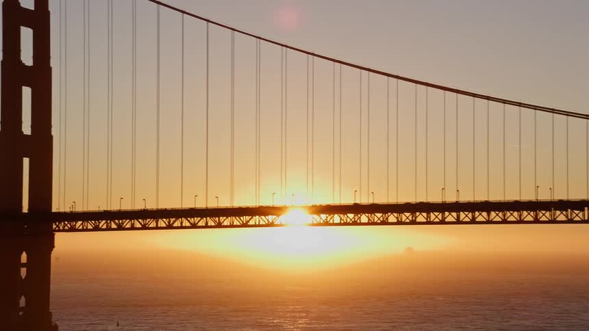 Aerial scene of the golden bridge with the silhouette of vehicle traffic and the sunset on the horizon
