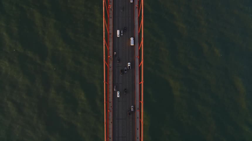 Vehicles drive over a bridge to reach the shore