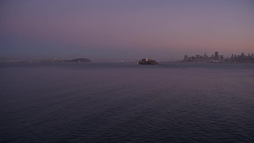 Aerial panorama of a vast ocean with a metropolis on the horizon on a morning with a purple sky