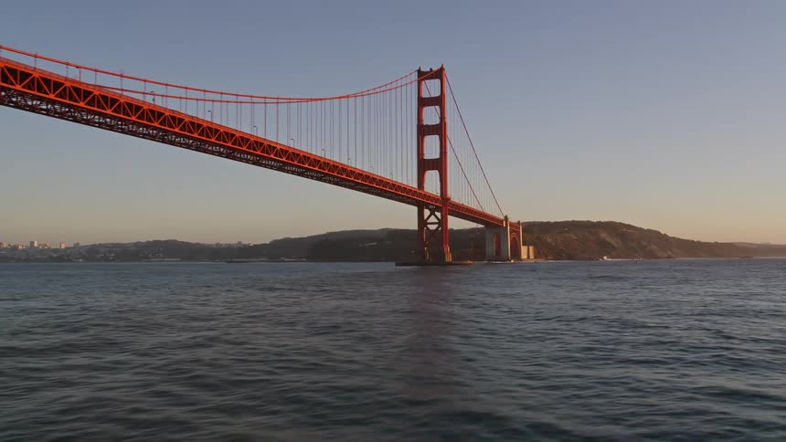 Water flows under the golden gate bridge with the city skyline in the background