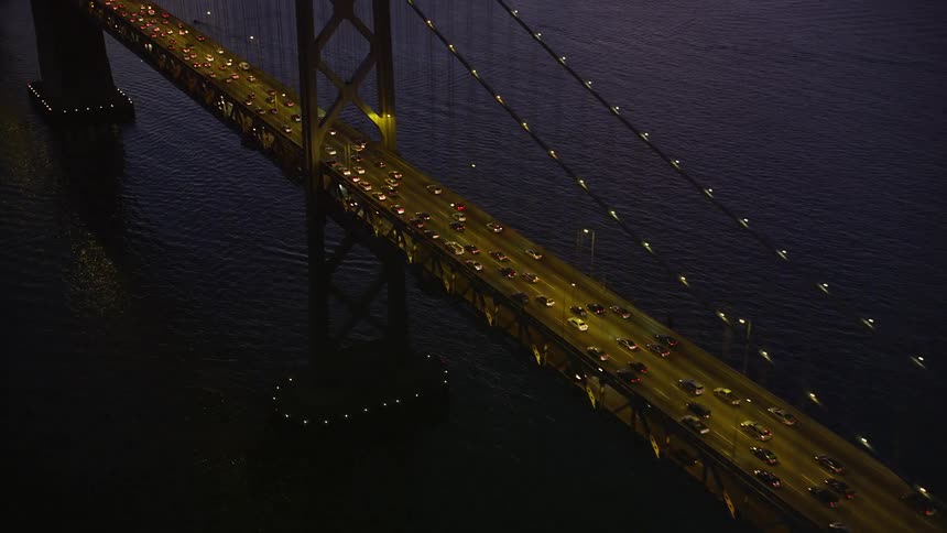 Aerial panorama of a bridge over the sea with vehicle traffic and in the background a metropolis with a purple and reddish sky