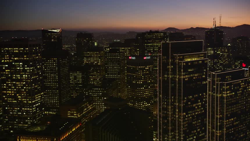 The tall buildings are brightly lit at sunset