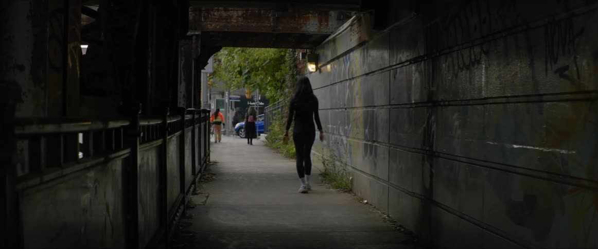A woman strides through a tunnel in a city