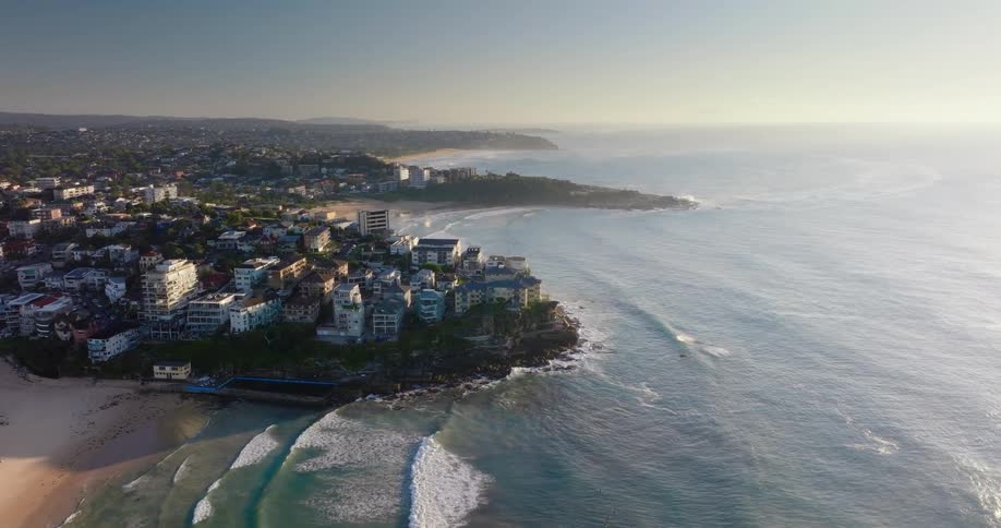 Aerial panorama of the sea arriving at the coast with a beach and an urban city in a morning