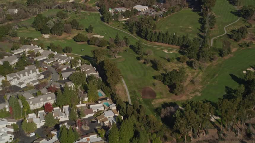 People play golf on a course in a suburban area